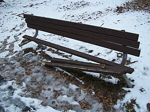 Picture of a broken park bench in winter with snow on the ground.