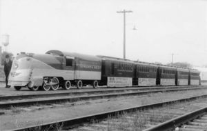© Photo: Lucius Beebe A scale replica of Locomotive #3460 and the Chief sits trackside at Stillwater, Oklahoma on Armistice Day, 1939. The sides of the cars are adorned with banners touting the many benefits of travelling to California (U.S. state) on the Santa Fe.